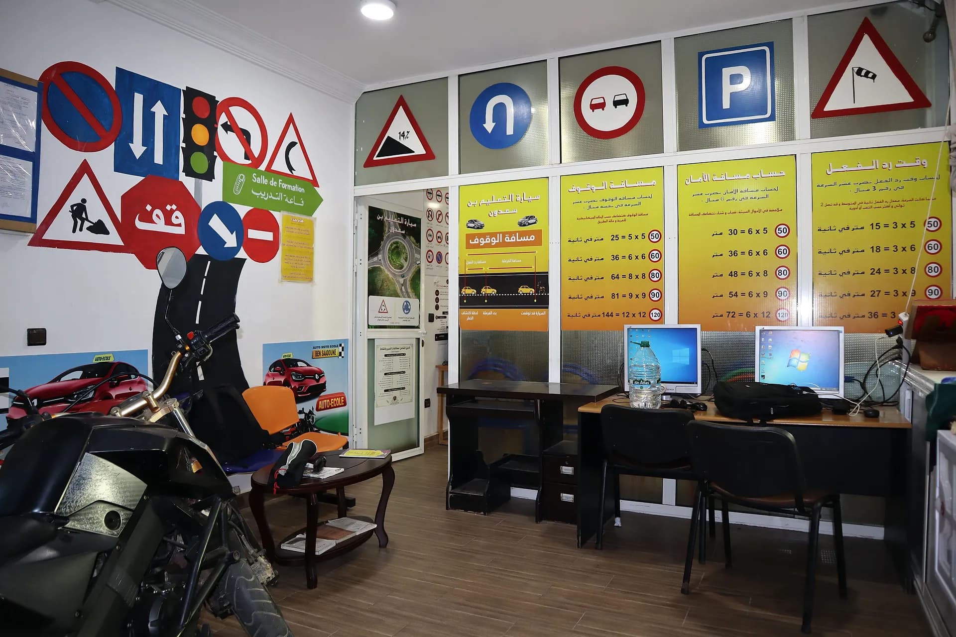 Accueil de l’Auto-École Bensaadoun : fresque de panneaux, tableaux des distances d’arrêt et de sécurité, postes informatiques et moto-école